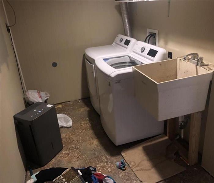 visible water damage on floor and walls in a laundry room